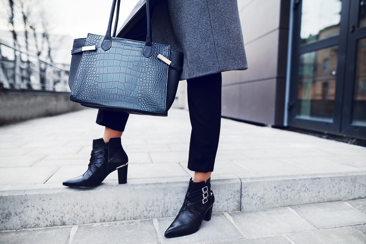 Woman posing with a leather crocodile skin handbag