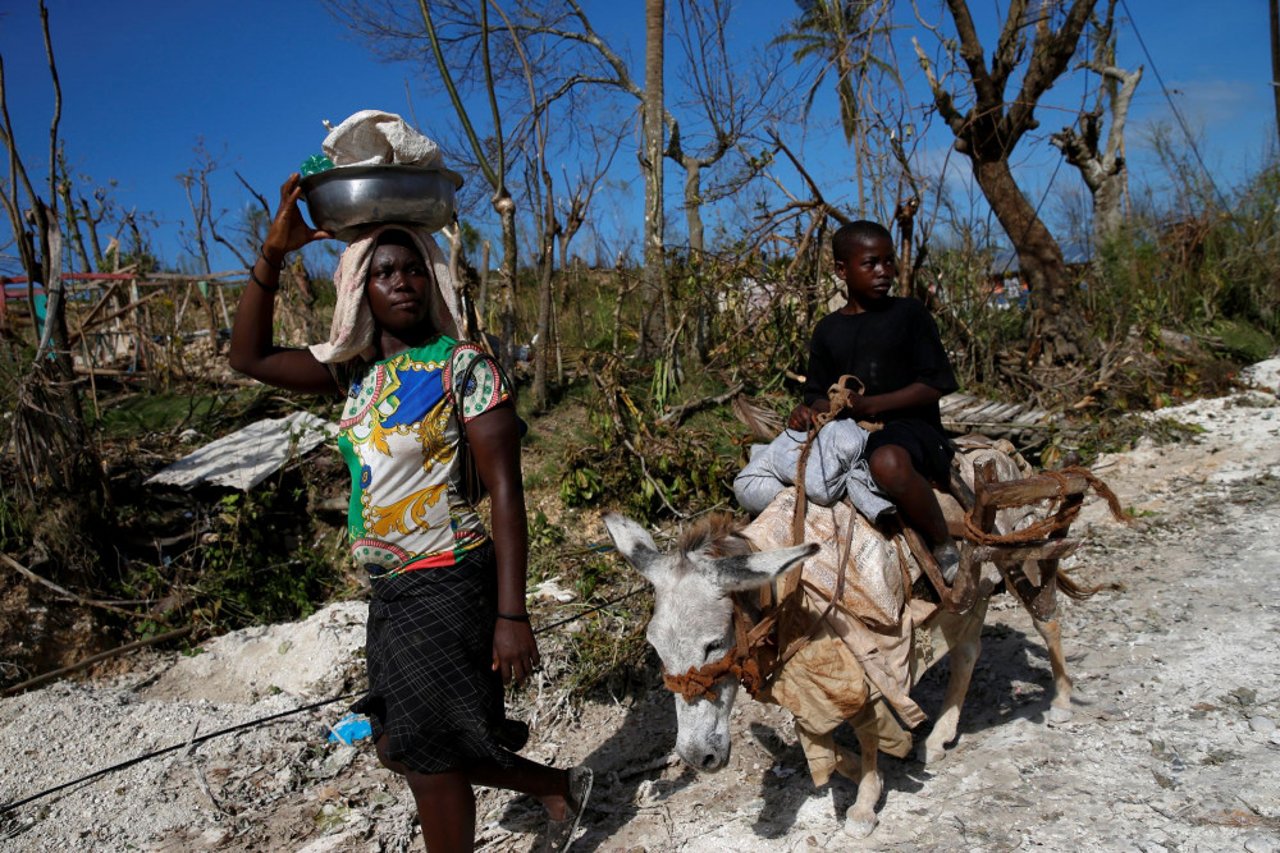 woman-and-child-riding-a-donkey-pass-by-destroyed-houses-after-hurricane-matthew-hit-haiti
